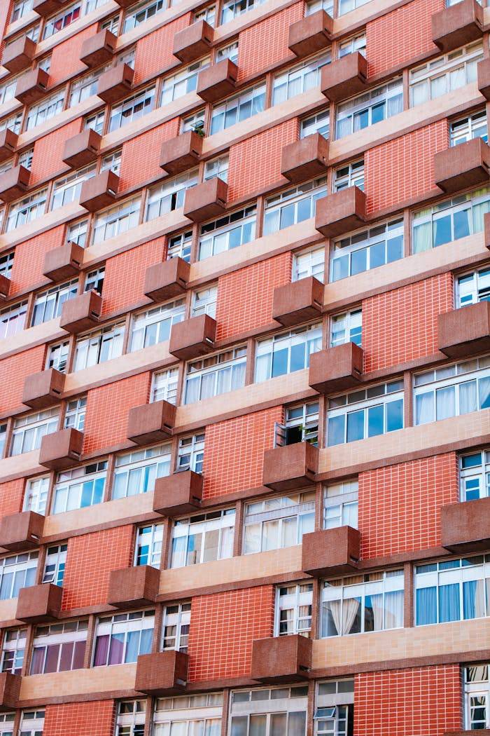 Close-up of a red brick apartment facade showcasing multiple windows and balconies.